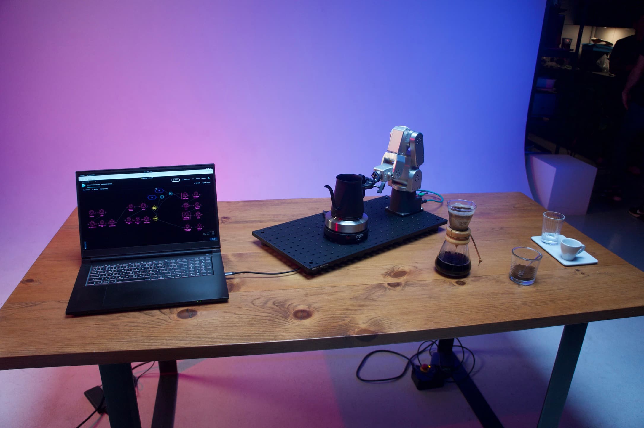 Flojoy robotics platform with laptop showing visual programming interface and robotic arm